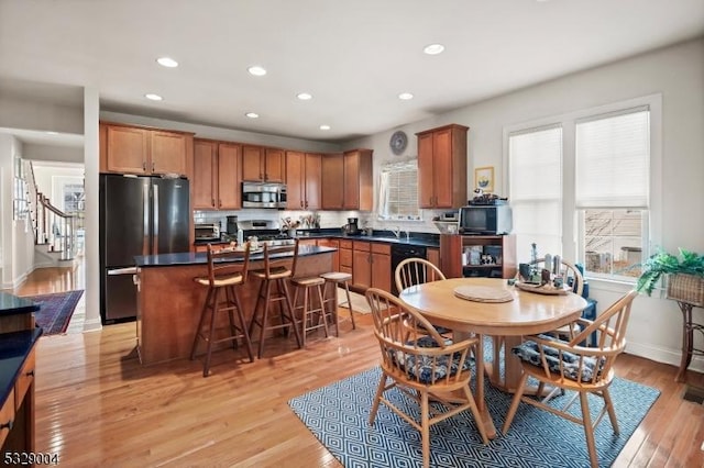 kitchen featuring a kitchen bar, stainless steel appliances, sink, a center island, and light hardwood / wood-style floors