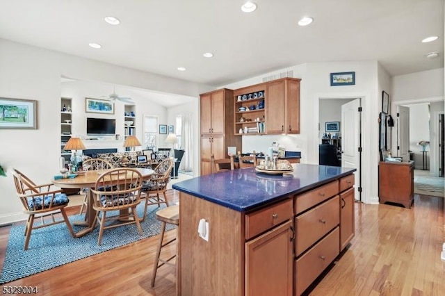 kitchen with a center island, light hardwood / wood-style flooring, ceiling fan, and a breakfast bar area