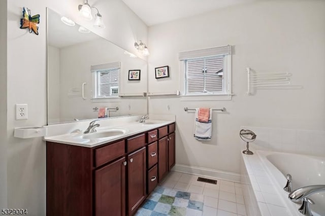 bathroom with tiled tub, tile patterned flooring, and vanity