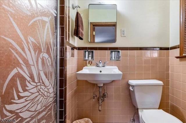 bathroom with toilet and tile walls