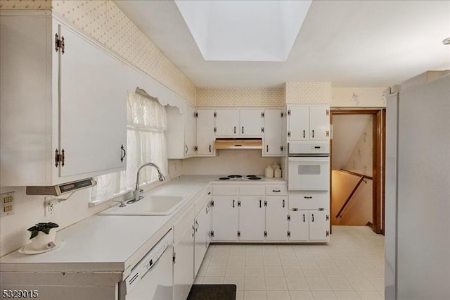 kitchen featuring white cabinets, white appliances, sink, and a skylight