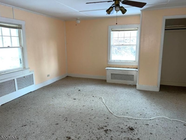 unfurnished bedroom featuring ceiling fan, carpet floors, and radiator