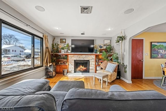 living room with a stone fireplace and light hardwood / wood-style flooring