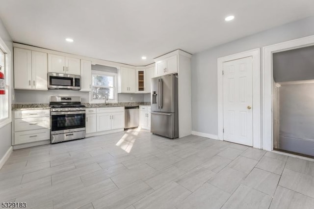 kitchen with white cabinetry, sink, light stone countertops, and appliances with stainless steel finishes