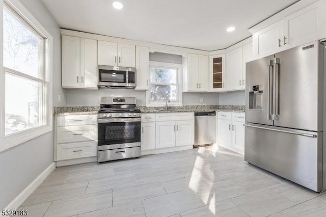 kitchen featuring light stone counters, plenty of natural light, white cabinets, and stainless steel appliances