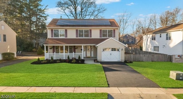 view of front facade featuring solar panels, covered porch, and a front lawn