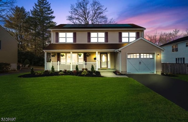 view of front facade with a lawn, a porch, and solar panels