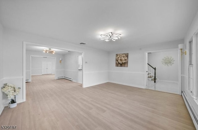 unfurnished room with baseboard heating, light hardwood / wood-style flooring, and a chandelier