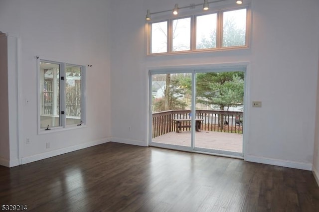 unfurnished living room with dark hardwood / wood-style flooring and a towering ceiling