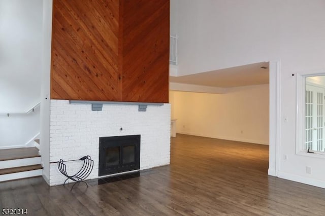 living room with dark hardwood / wood-style flooring, a towering ceiling, and a fireplace