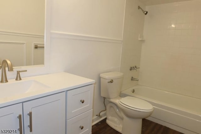 full bathroom with hardwood / wood-style floors, vanity, tiled shower / bath combo, and toilet