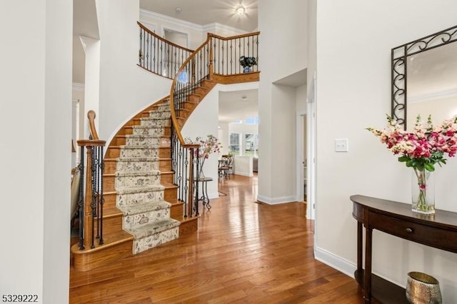 entryway featuring hardwood / wood-style flooring, a towering ceiling, and crown molding