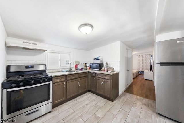 kitchen with dark brown cabinets, stainless steel appliances, extractor fan, and sink