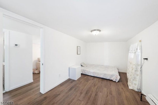 unfurnished bedroom with dark hardwood / wood-style floors and baseboard heating