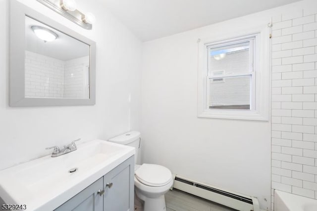 full bathroom featuring vanity, toilet, tiled shower / bath, and a baseboard heating unit