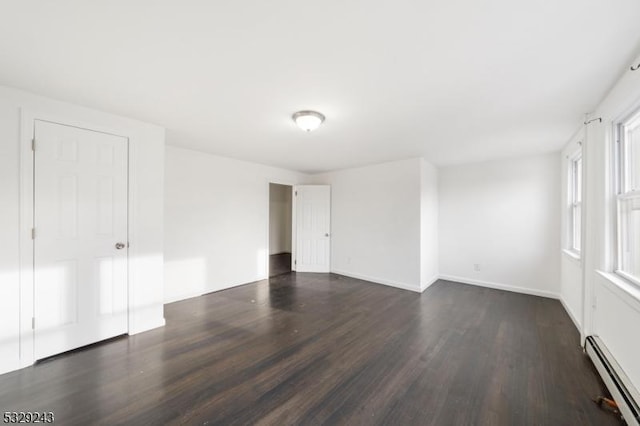 spare room featuring baseboard heating and dark wood-type flooring