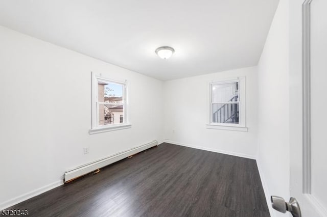 spare room with baseboard heating and dark wood-type flooring