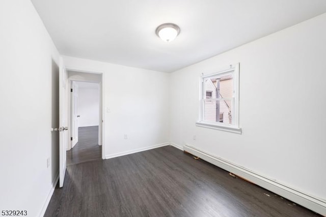 spare room with a baseboard radiator and dark hardwood / wood-style floors