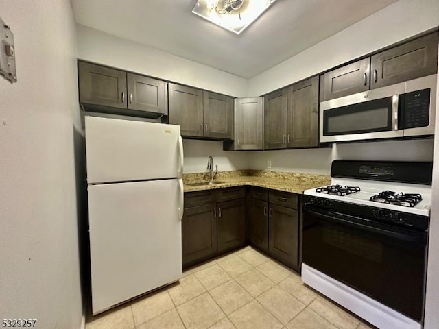 kitchen with light stone countertops, white appliances, dark brown cabinetry, sink, and light tile patterned floors