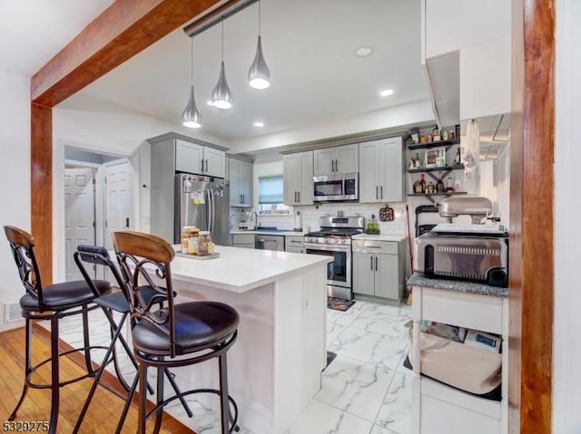 kitchen with gray cabinetry, decorative light fixtures, decorative backsplash, and stainless steel appliances