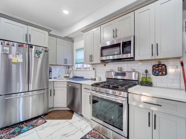 kitchen with gray cabinets, sink, backsplash, and appliances with stainless steel finishes