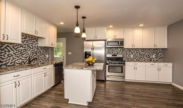 kitchen with pendant lighting, white cabinets, appliances with stainless steel finishes, a kitchen island, and dark hardwood / wood-style flooring