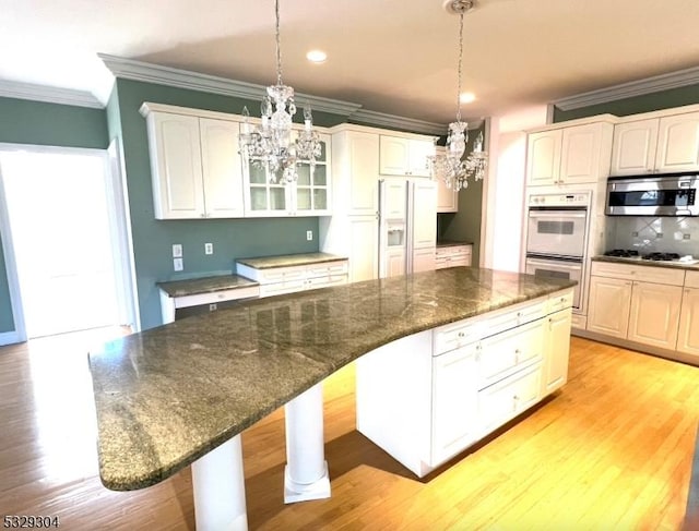 kitchen with a kitchen bar, white appliances, a kitchen island, and hanging light fixtures