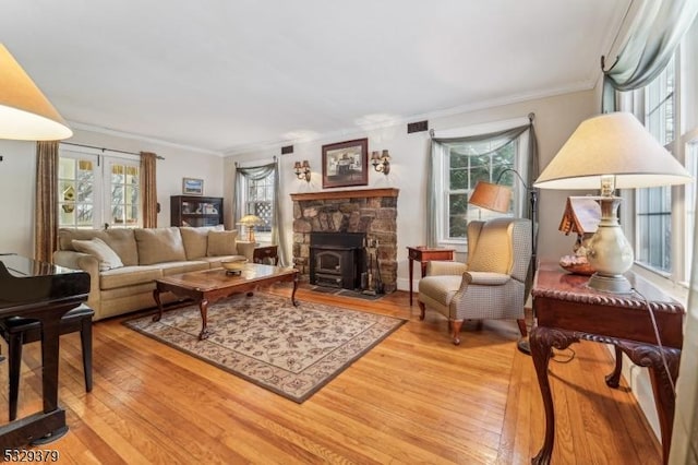 living room with french doors, wood-type flooring, ornamental molding, and a wood stove