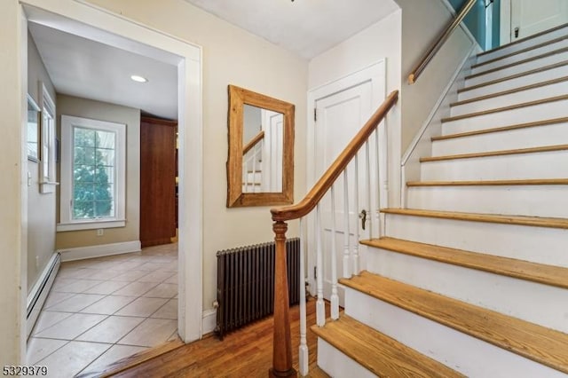 stairs featuring tile patterned floors, radiator heating unit, and baseboard heating