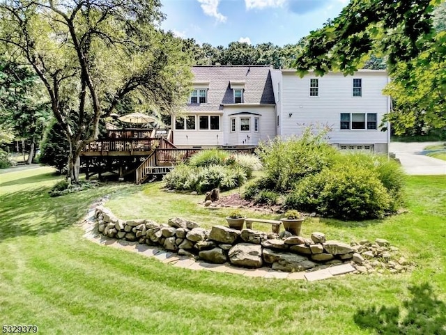 rear view of house featuring a lawn and a wooden deck