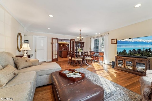 living room featuring hardwood / wood-style floors, ornamental molding, and a notable chandelier