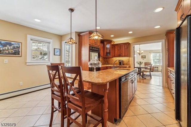 kitchen with dishwasher, pendant lighting, a kitchen island with sink, black refrigerator, and light tile patterned floors