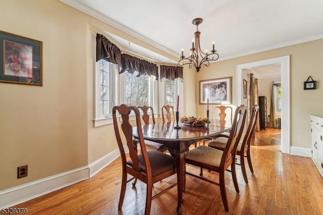 dining room featuring ornamental molding, light wood-type flooring, plenty of natural light, and a notable chandelier