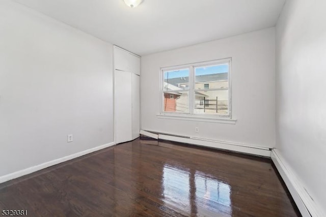 empty room with dark wood-type flooring and a baseboard radiator