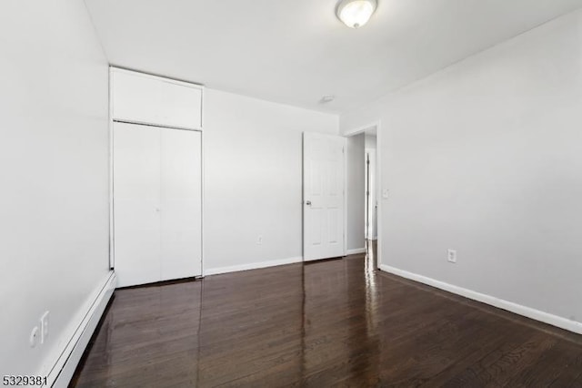 unfurnished bedroom with dark hardwood / wood-style flooring, baseboard heating, and a closet