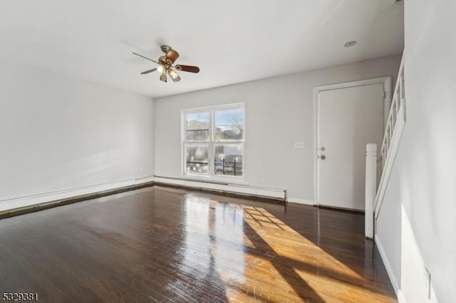 empty room featuring dark hardwood / wood-style flooring, a baseboard radiator, and ceiling fan