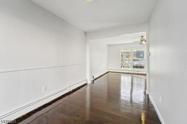 spare room featuring ceiling fan, a baseboard radiator, and dark hardwood / wood-style floors