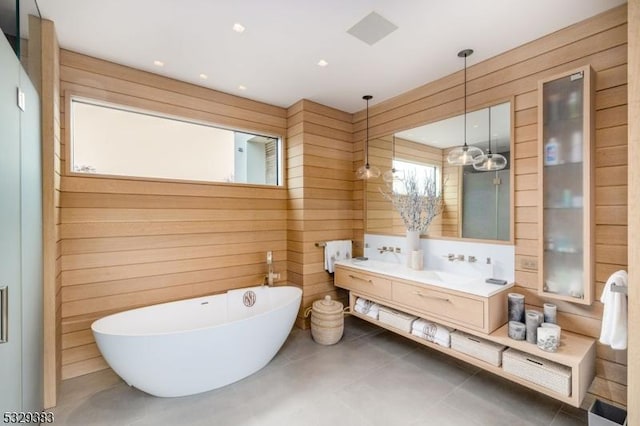 bathroom featuring a bath, vanity, and wooden walls