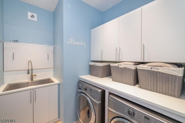 laundry room with washing machine and dryer, sink, and cabinets