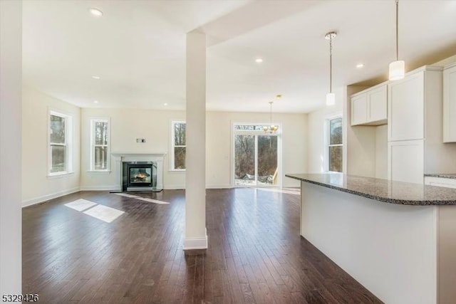 kitchen featuring dark stone countertops, pendant lighting, dark hardwood / wood-style floors, and white cabinets