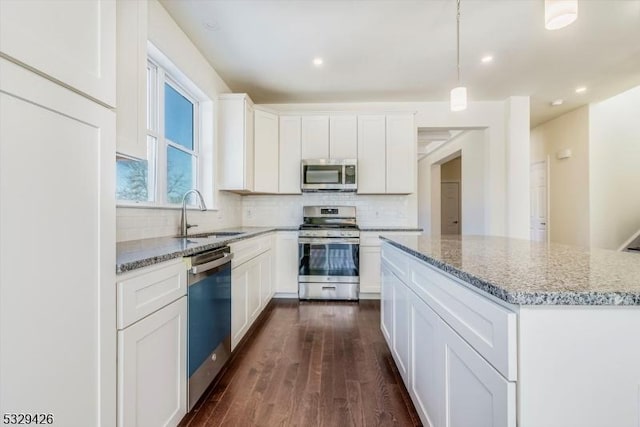 kitchen featuring sink, white cabinetry, stainless steel appliances, light stone counters, and a kitchen island