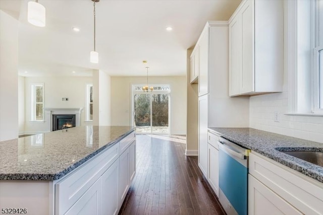 kitchen featuring pendant lighting, dishwasher, white cabinetry, a center island, and decorative backsplash