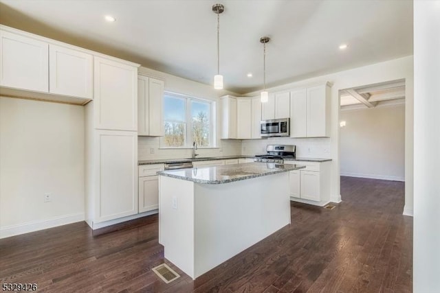 kitchen featuring hanging light fixtures, appliances with stainless steel finishes, white cabinets, and light stone counters