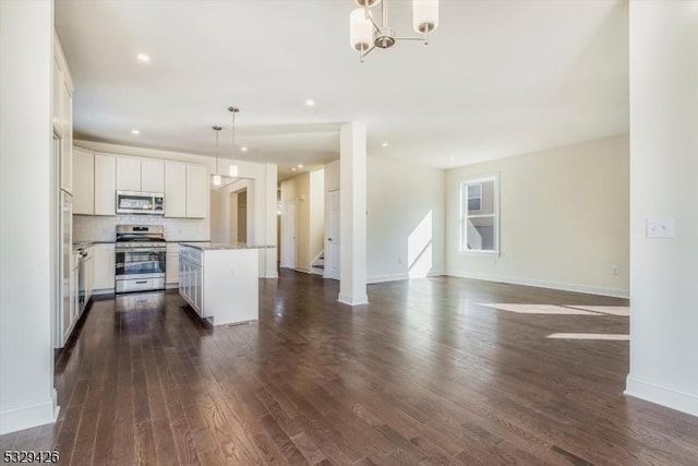 kitchen featuring pendant lighting, white cabinetry, stainless steel appliances, dark hardwood / wood-style floors, and a center island