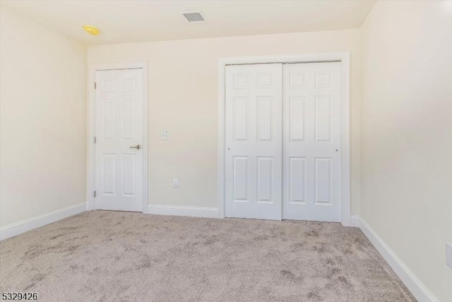 unfurnished bedroom with a closet and light carpet