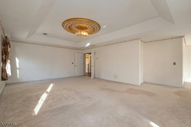 spare room featuring a tray ceiling and carpet floors