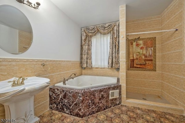 bathroom with separate shower and tub and tile walls