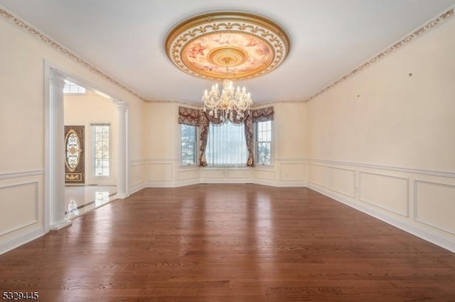 unfurnished room featuring dark hardwood / wood-style floors, an inviting chandelier, and decorative columns