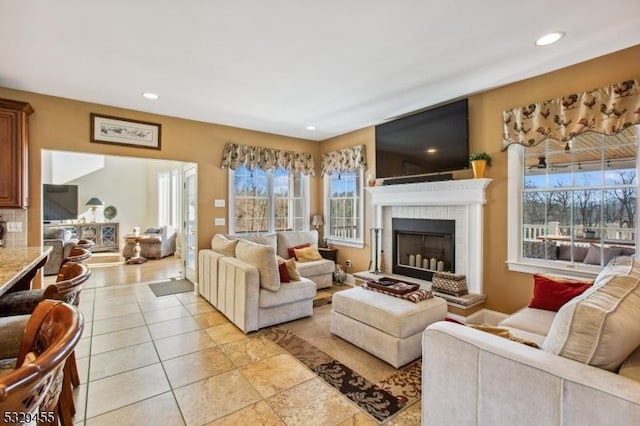 living room with a fireplace, light tile patterned floors, and plenty of natural light