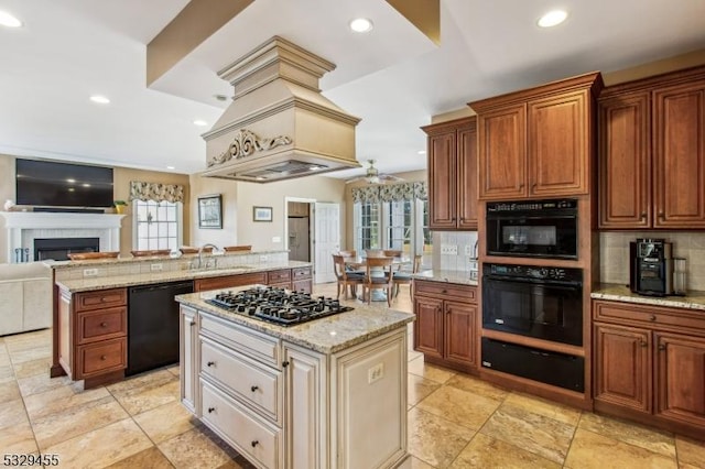 kitchen with black appliances, a kitchen island, light stone countertops, and sink